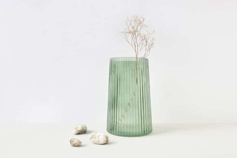 Delicate dried flower in a green glass vase, minimalist style, Lake Michigan Wines inspired, elegant decor element.